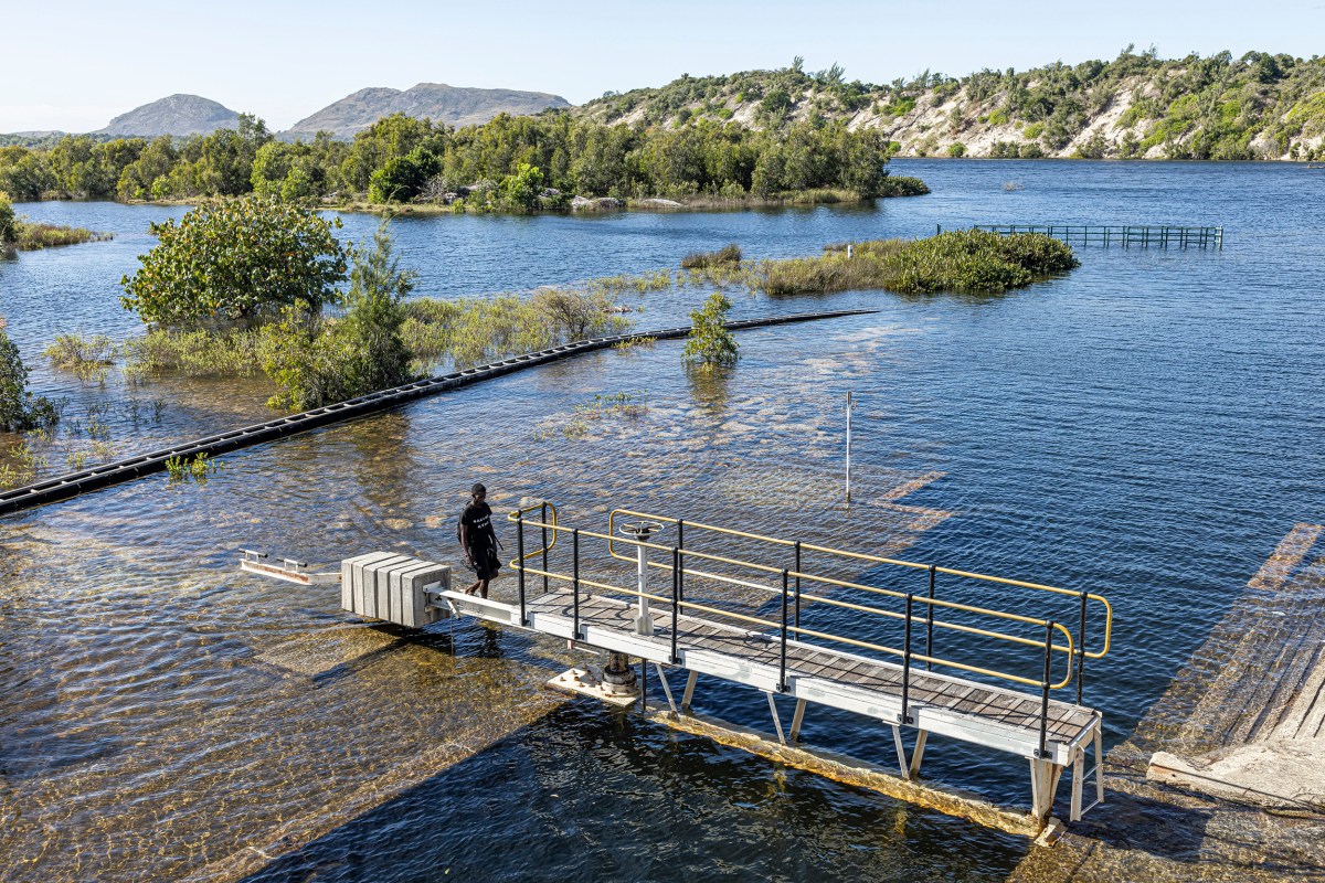 A man walks across the weir built by QMM in Lake Ambavarano in Fort-Dauphin, Madagascar, on July 9, 2023. The inundations of salt water from the sea have stopped because of the physical barrier, which essentially has converted Ambavarano into a freshwater lake. Nearly all the species of fish that thrived in the brackish water conditions are now lost.